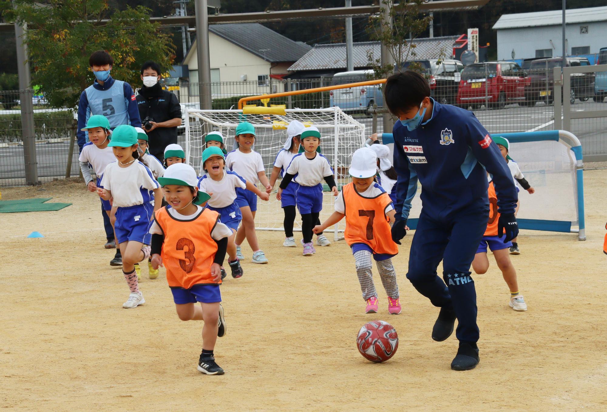 カマタマの選手とボールを追いかける子どもたち