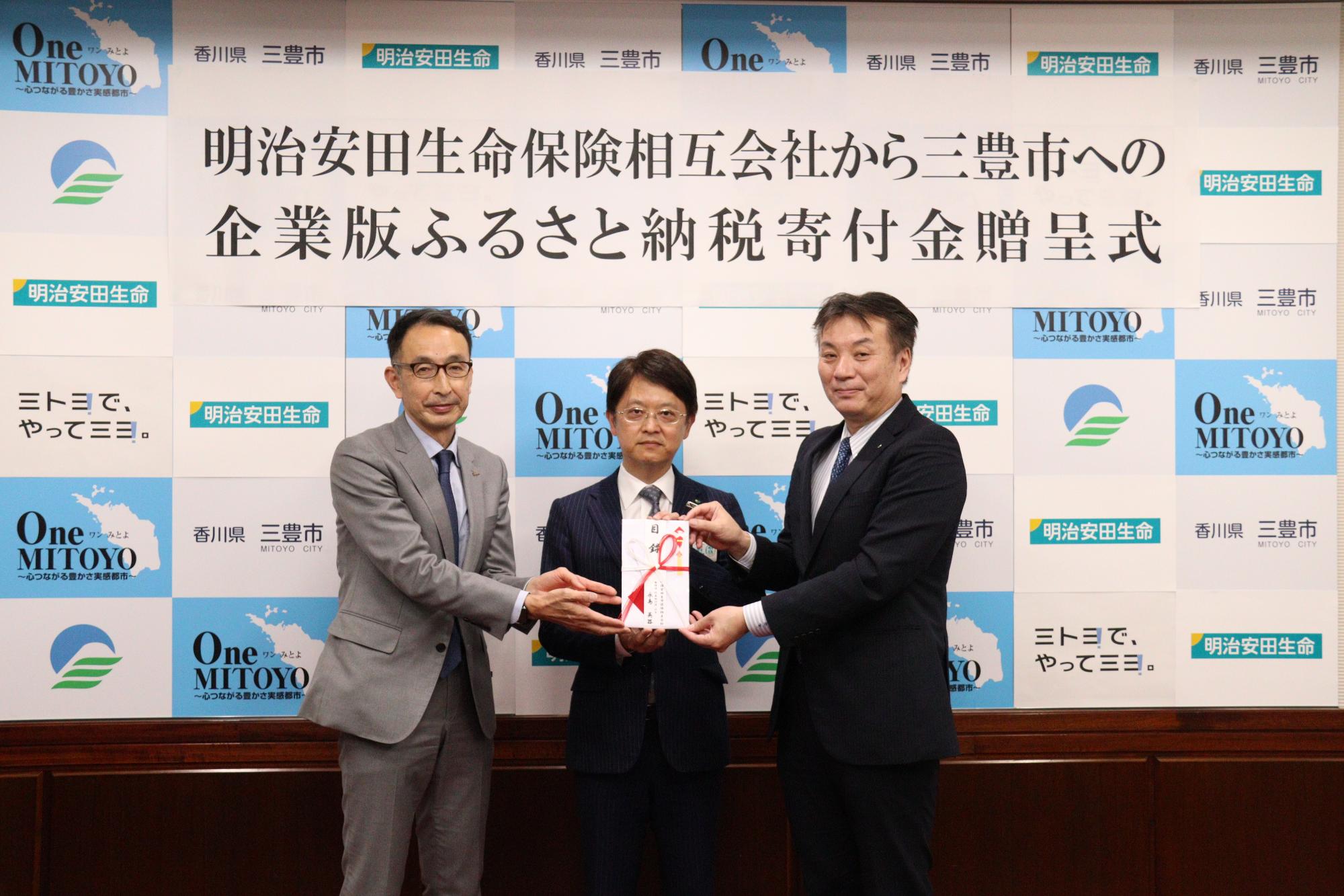 協定書を持つ（左から）カマタマーレ讃岐の池内秀樹社長、明治安田生命相互会社の佐々木高松支店長、山下市長