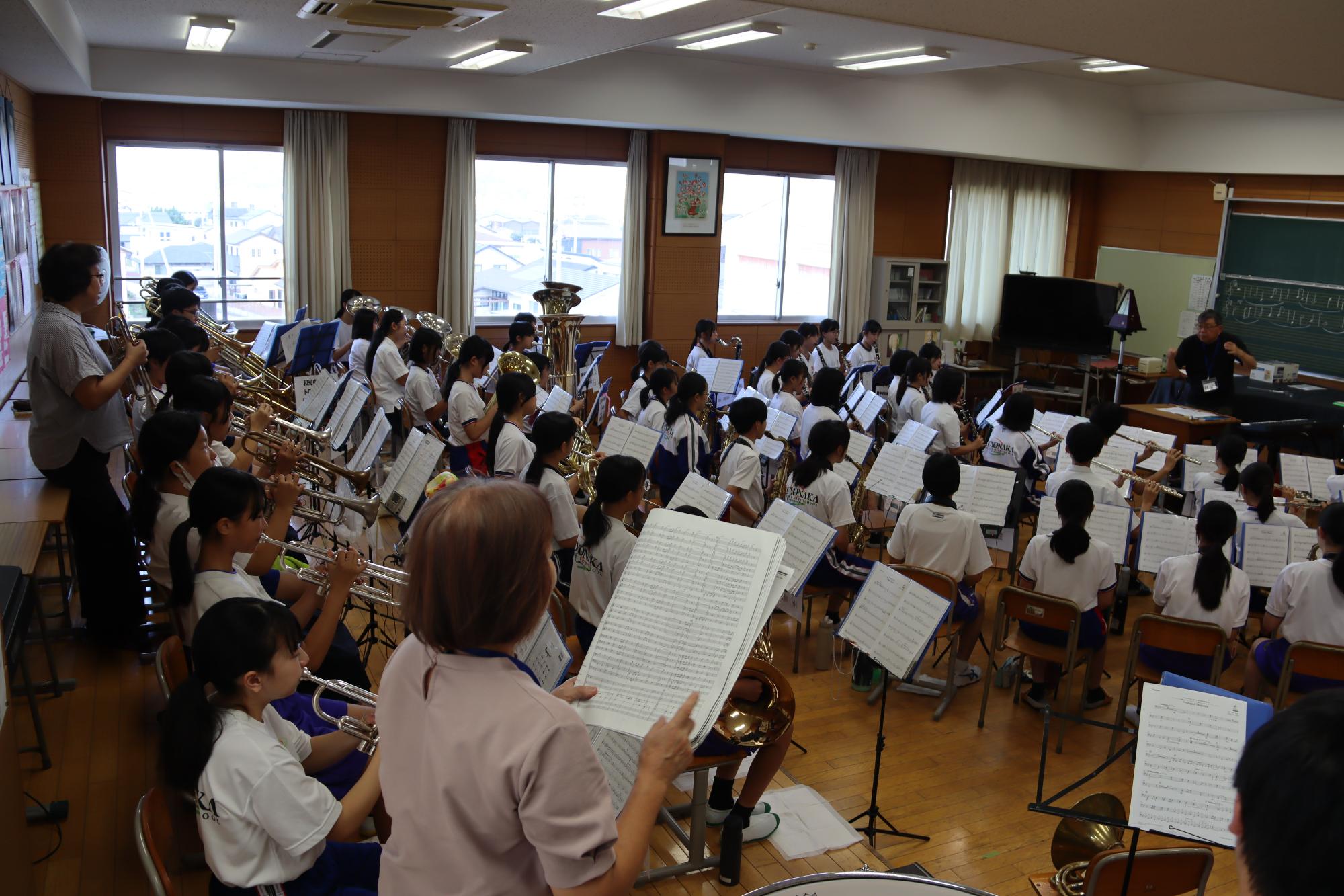 指揮者の指導のもと、合奏の練習を行う吹奏楽部員