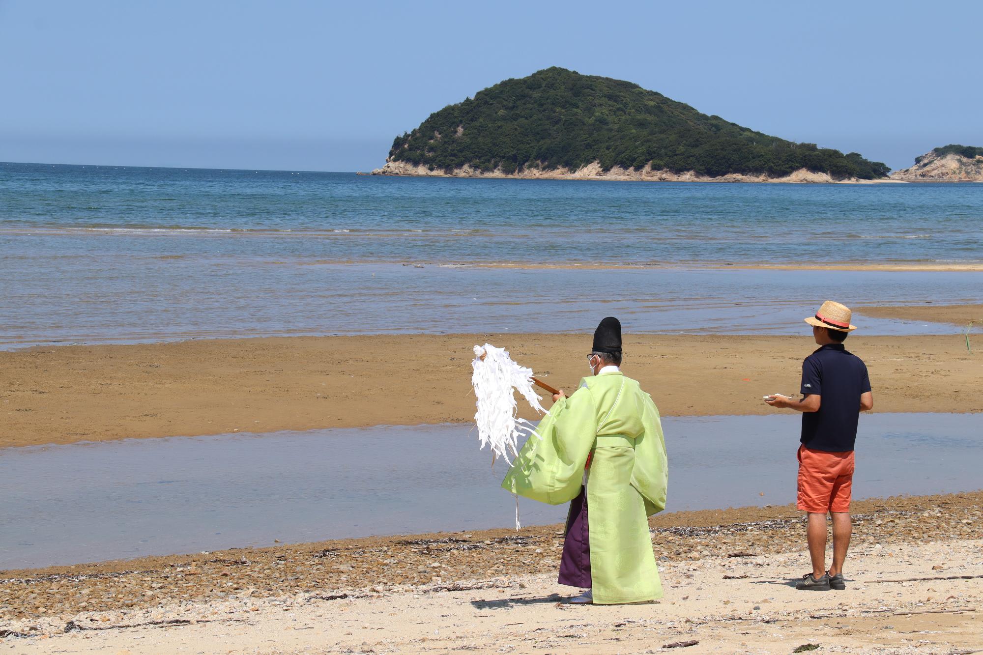 父母ヶ浜へ神主がお神酒をそそぐ